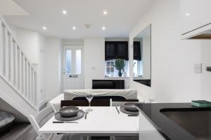 a white living room with a table and a dining room at Stylish 2BR Cottage in Chesham in Chesham