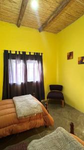 a room with two beds and a window with a chair at Casa Manuel in Tinogasta +4 photos