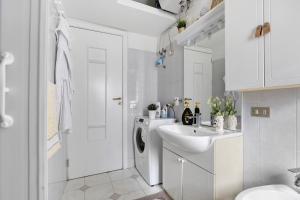 a white bathroom with a sink and a washing machine at A due passi dal mare in Oliveri +13 photos