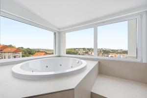 a white bathroom with a large tub in front of windows at Gran Hotel Suances Suites in Suances +33 photos