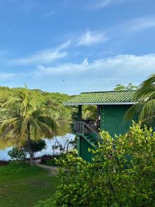a green house with a balcony and a body of water at Jardin Secreto in El Viejo