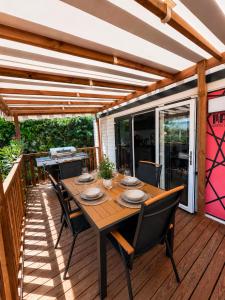 a wooden deck with a wooden table and chairs at Camping Oléron Cap Soleil MH Climatisé in Saint-Denis-dʼOléron