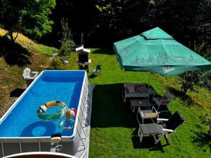 a swimming pool with an umbrella and chairs and a swimming pool at Brvnaria in Slatina Varoš