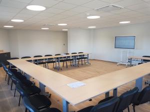 a conference room with tables and chairs and a screen at The Originals City Hôtel-Restaurant-Terrasse du PAarc Gravelines Dunkerque in Gravelines