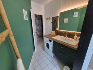 a bathroom with a sink and a washing machine at Petunia in Commentry