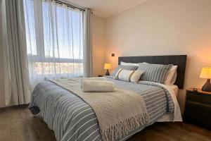 a bedroom with a bed and a large window at Vista Laguna Oriente By Andes Plus in Concepción