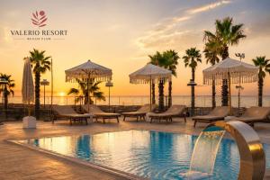 a pool at a resort with chairs and umbrellas at Valerio Resort beach club in Margherita di Savoia