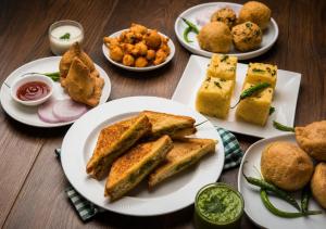 a table with plates of sandwiches and other foods at Eloras Inn in Siliguri
