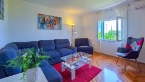 a living room with a blue couch and a table at Mendy Sea View Apartment in Kaštela