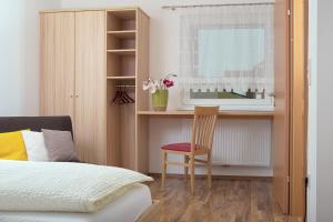 a bedroom with a bed and a desk and a chair at Gästehaus Lackenblick in Illmitz