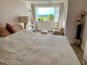 a bedroom with a large white bed and a window at Magic of Avalon in Glastonbury