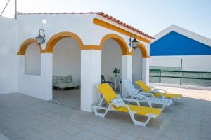 a patio with two yellow chairs and a table at Casa dos Alpendres in Avis