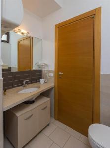 a bathroom with a toilet and a wooden door at Giardino del carrubo in Marina di Ragusa +18 photos