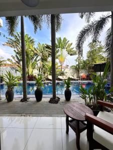 a pool with palm trees and a bench and a table at Angkor Sweet Night Hotel in Siem Reap