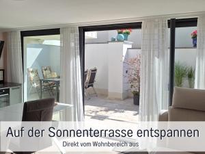 an open glass door with curtains in a living room at Die Perle am Teich ist Ihre exklusive Ferienwohnung mit Klimaanlage und großer Terrasse im Harz in Ballenstedt