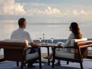 a man and woman sitting at a table with wine glasses at V Villas Maldives at Mirihi - MGallery Collection in Mandhoo