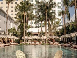 a pool at a hotel with chairs and palm trees at Delano Miami Beach in Miami Beach