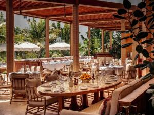 a dining room with tables and chairs and trees at Delano Miami Beach in Miami Beach