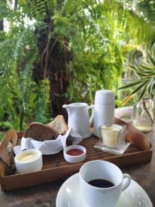 a tray with bread and a cup of coffee and butter at Pousada Deus mim Deu in Caraíva +14 photos