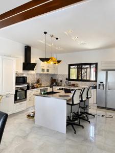 a kitchen with white cabinets and a island with bar stools at Le Refuge du Lac Rose in Ouayembame