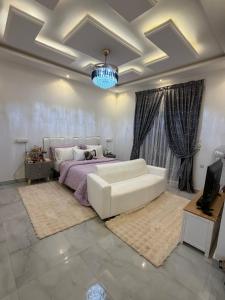 a living room with a white couch and a bed at Le Refuge du Lac Rose in Ouayembame