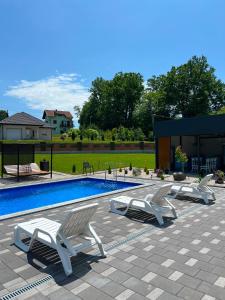 two white lounge chairs sitting next to a swimming pool at Villa Jovičić in Prijedor