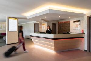 Eine Frau geht an einem Empfangstresen in einer Lobby vorbei in der Unterkunft Warmthotel in Rom