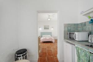 a kitchen with a microwave and a room with a bed at Casa Veronica in Arona