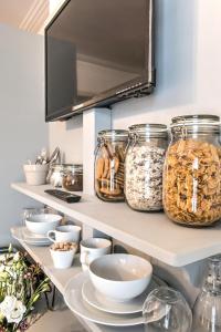 a pantry shelves filled with bowls and jars of food at April House Weybridge - Boutique Guesthouse in Weybridge