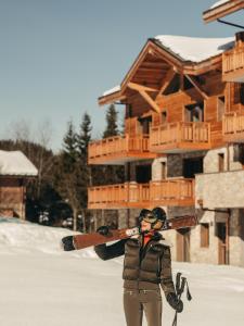 a person holding skis in front of a log cabin at Barma Résidence & Appartements in Courchevel