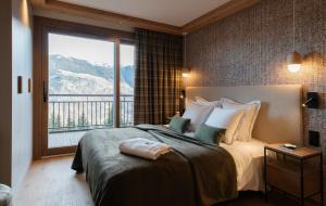 a bedroom with a large bed with a large window at Barma Résidence & Appartements in Courchevel