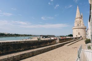 a building with a tower next to a body of water at Vue mer, sur le port, près des tours in La Rochelle