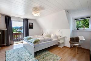 a white bedroom with a bed and a window at Haslehaus in Feldberg