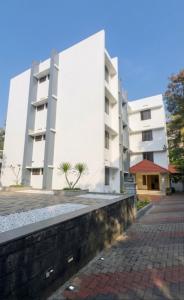 a white building with a brick walkway in front of it at Tech City Hotel Trivandrum in Trivandrum +29 photos