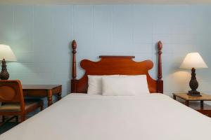 a bedroom with a large bed with a wooden headboard at Waikiki Heritage Hotel in Honolulu