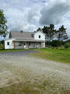a white farm house with a gravel driveway at maison chez René in Saint-Malachie