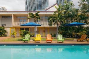 a hotel with chairs and umbrellas next to a swimming pool at Waikiki Heritage Hotel in Honolulu