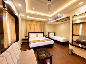 a hotel room with two beds and a couch at Hotel A One Luxury - Premium Stay Puri Beach in Puri