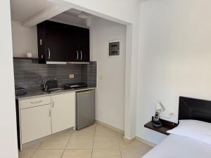 a kitchen with black cabinets and a bed in a room at Tomi garden apartment in Sarandë