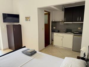 a bedroom with a white bed and a kitchen at Tomi garden apartment in Sarandë