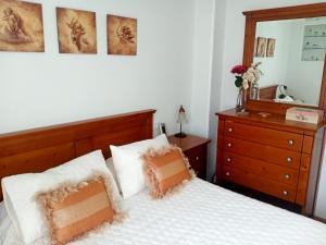 a bedroom with a bed and a dresser and a mirror at Casa de Concha in Burela de Cabo
