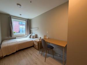 a bedroom with a bed and a desk and a window at Kongens Gate Rooms in Kristiansand