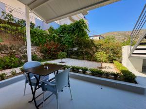 a table and chairs on a patio with a garden at Tomi garden apartment in Sarandë
