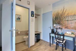 a bathroom with a toilet and a desk with a chair at Les Gîtes Shu-no in Pléhédel