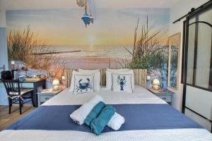 a bedroom with a bed with a painting of the beach at Les Gîtes Shu-no in Pléhédel