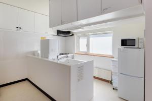 a white kitchen with a refrigerator and a microwave at つぐ屋札幌 in Sapporo