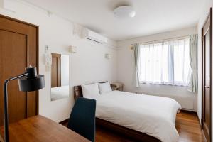 a bedroom with a bed and a desk and a window at つぐ屋札幌 in Sapporo