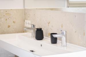 a bathroom sink with two faucets and two cups on it at Gratzenthal Boutique Apartments in Hollenstein an der Ybbs +70 photos