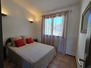 a bedroom with a bed with red pillows and a window at Fiori Di Santa Giulia in Porto-Vecchio