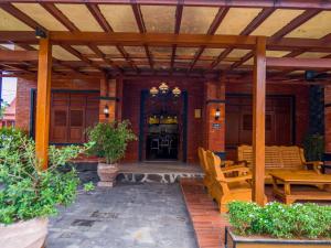 a patio with a wooden pergola and tables and chairs at Griya Mandara Homestay Prambanan in Bugisan